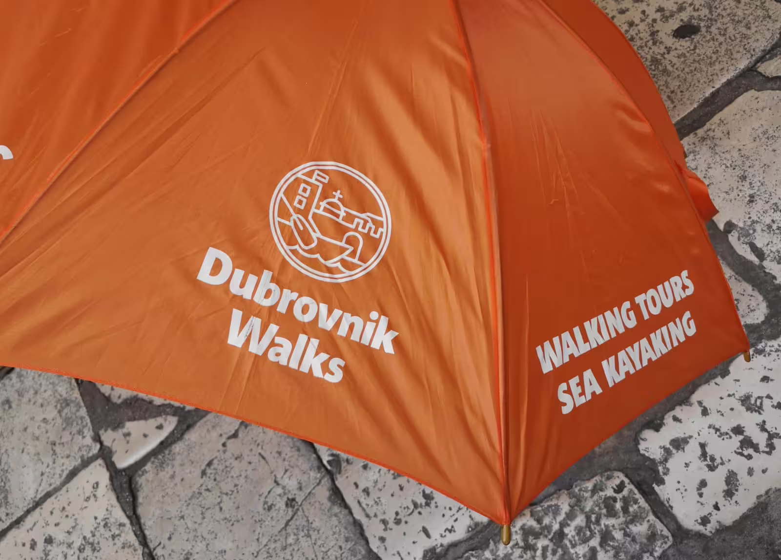 Orange Dubrovnik Walks umbrella promoting sea kayaking tours, ideal for Sea Kayaking & Snorkeling booking