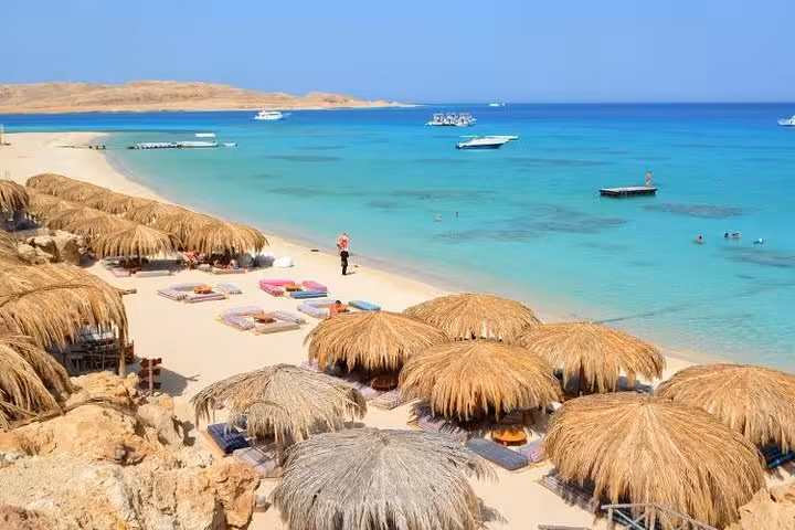 Orange Island beach near Hurghada with straw umbrellas, white sand and turquoise Red Sea on day trip