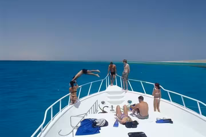 Boat deck on Orange Island cruise from Hurghada, guests sunbathing and diving into the Red Sea lagoon