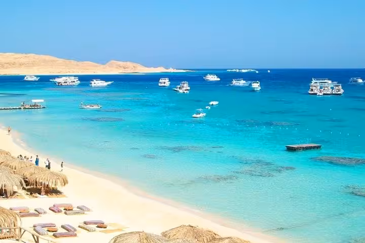 Orange Island boat trip from Hurghada with turquoise Red Sea lagoon, sandy beach, and yachts anchored offshore