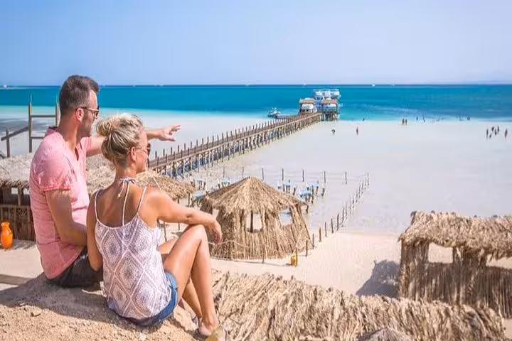 Couple overlooking Orange Island sandbar from Hurghada, pier and beach huts, ideal day trip from Makadi Bay