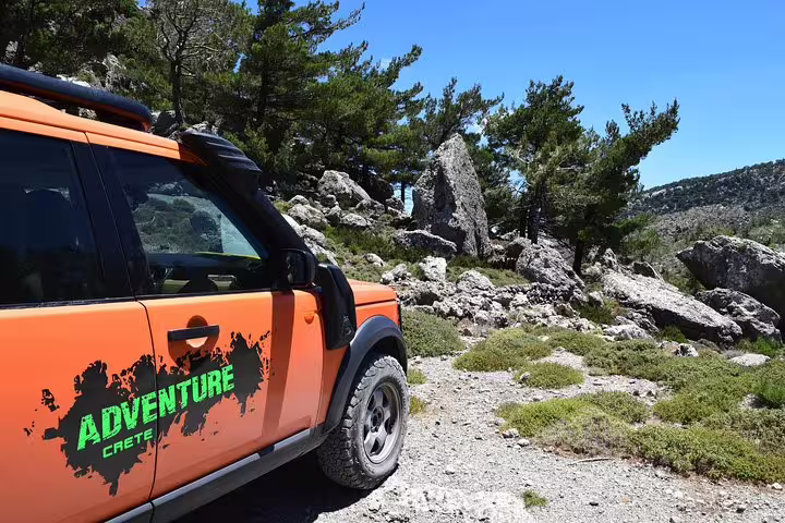 Orange Land Rover with 'Adventure Crete' branding on a rugged trail, ideal for a VIP luxury private 4x4 excursion.