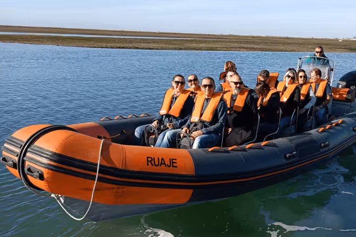 Orange RIB boat with passengers in life jackets on a Faro dolphin watching tour in the Algarve lagoon waters