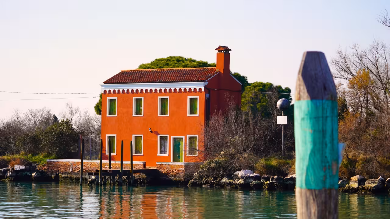 Orange waterfront house in Mazzorbo, Venice lagoon—quiet stop on Burano & Mazzorbo lace and history tour