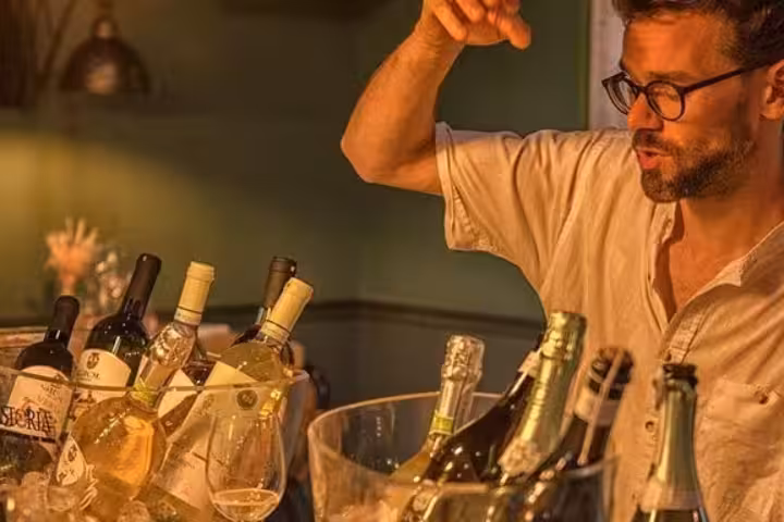 Wine enthusiast presenting a variety of organic wines in ice buckets during a tasting in Nice.