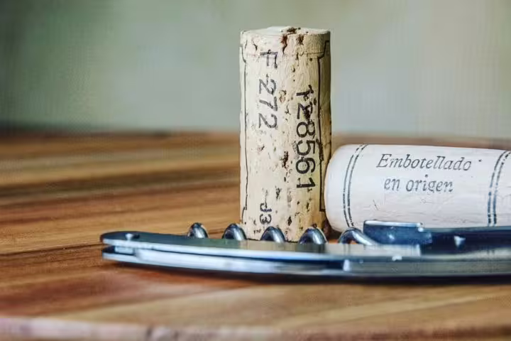 Wine corks and a corkscrew on a wooden table, symbolizing the authentic experience of a local winery lunch tour.