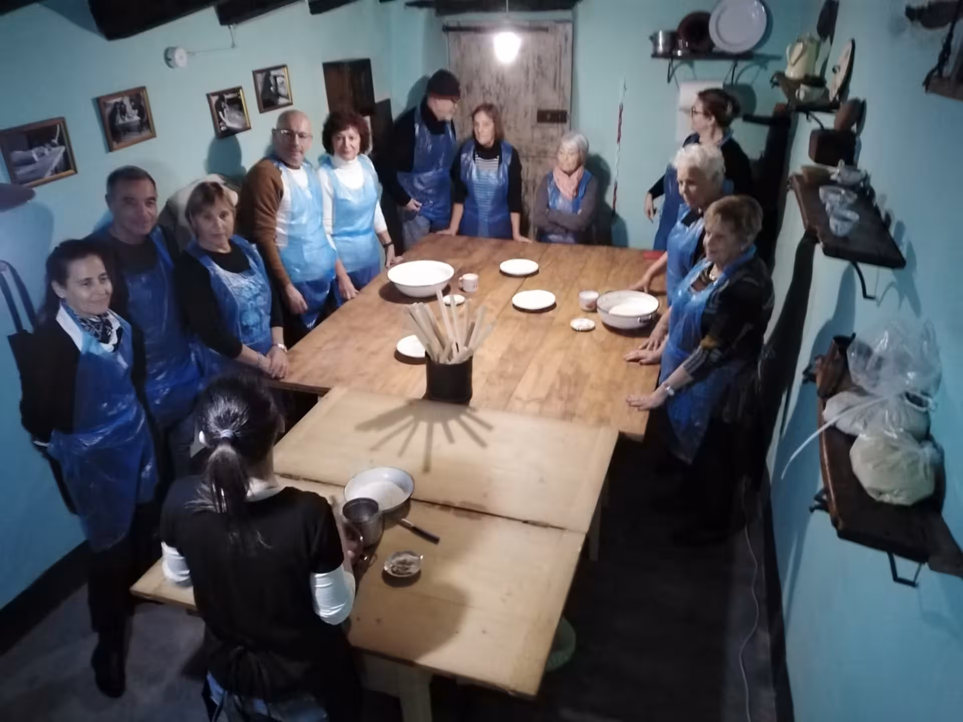 Group of people in aprons attending a carasau bread-making class at Orgosolo Bread Museum.