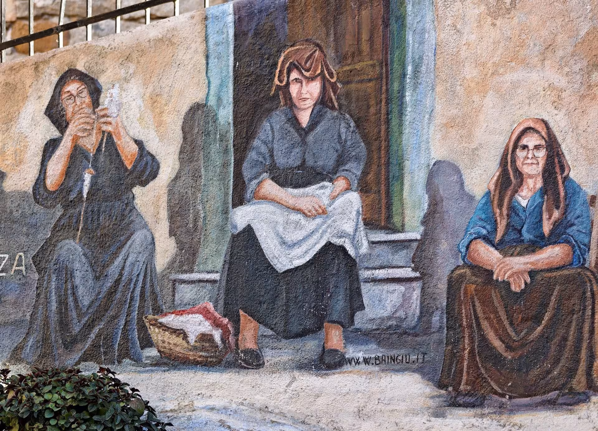 Historic mural in Orgosolo depicting three women engaged in traditional Sardinian activities.