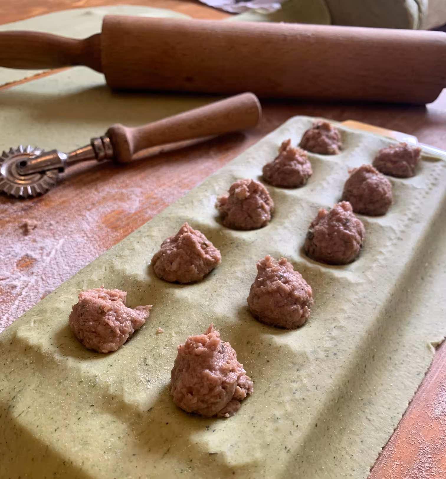 Close-up of fresh ravioli with meat filling being prepared on a floured surface during Oristano pasta workshop.