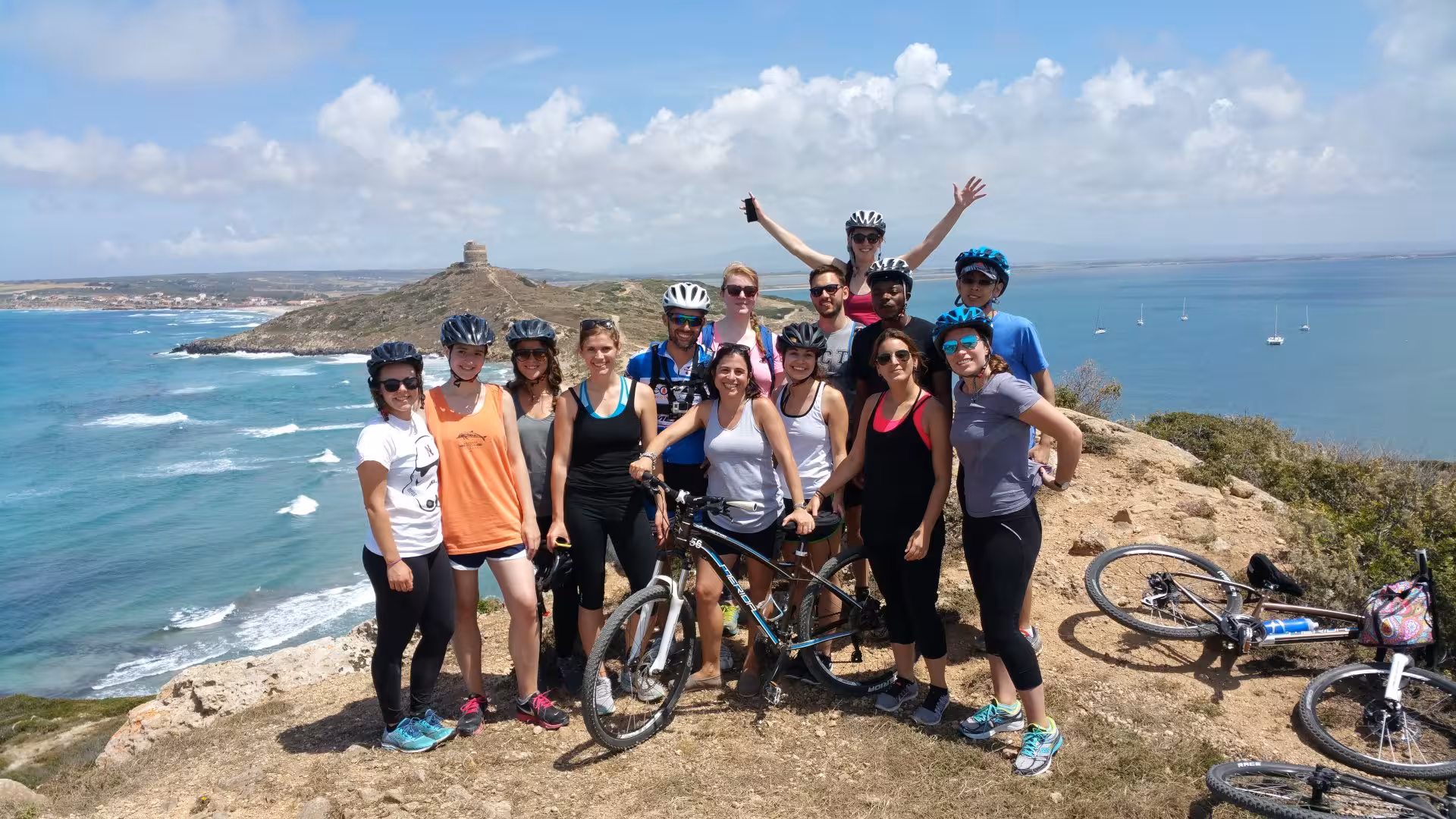 Group of cyclists enjoying a panoramic view of Sinis Peninsula coastline on a bike tour from Oristano.