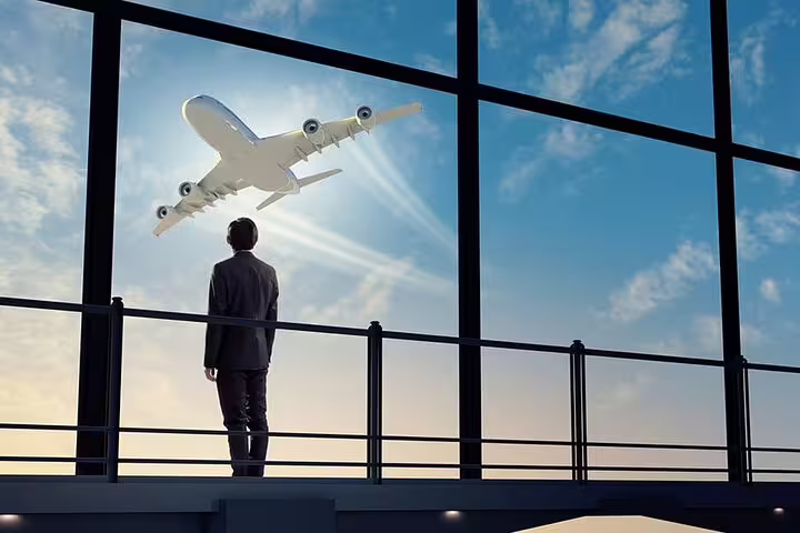 Traveler watching plane through airport windows, booking private transfer from Orly Airport to central Paris