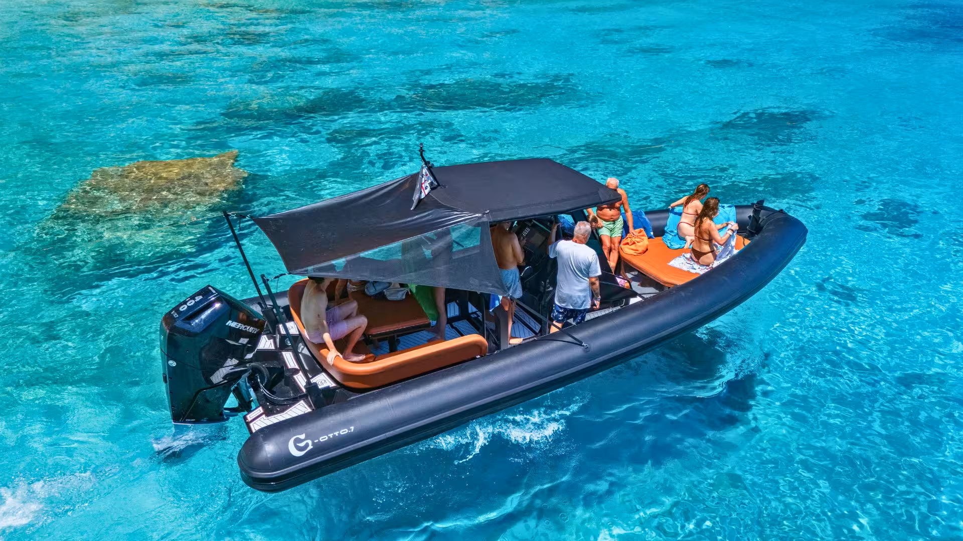 Travelers relax on a dinghy in the turquoise waters of Cala Luna, exploring the Sardinian coastline.