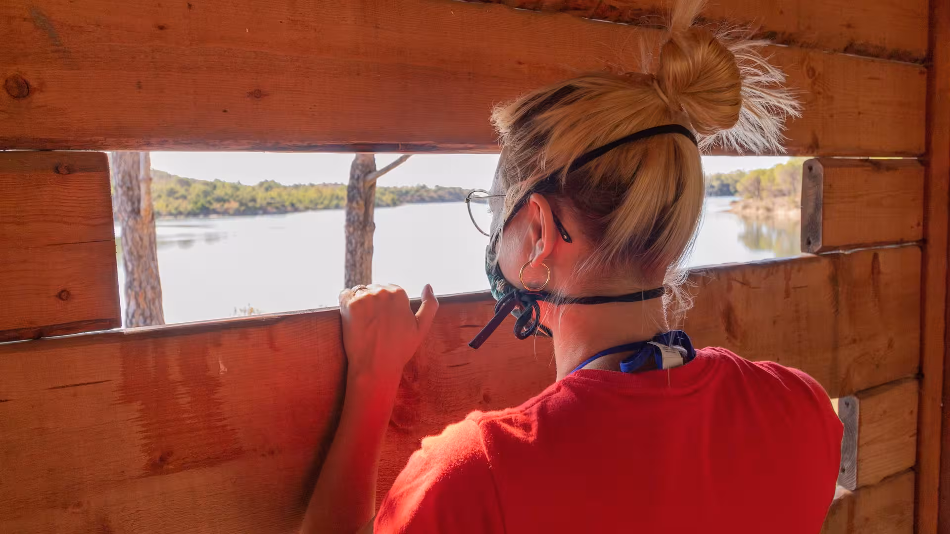 Tourist enjoying scenic view of Biderosa lagoon from a wooden birdwatching hut on a Jeep tour in Sardinia.