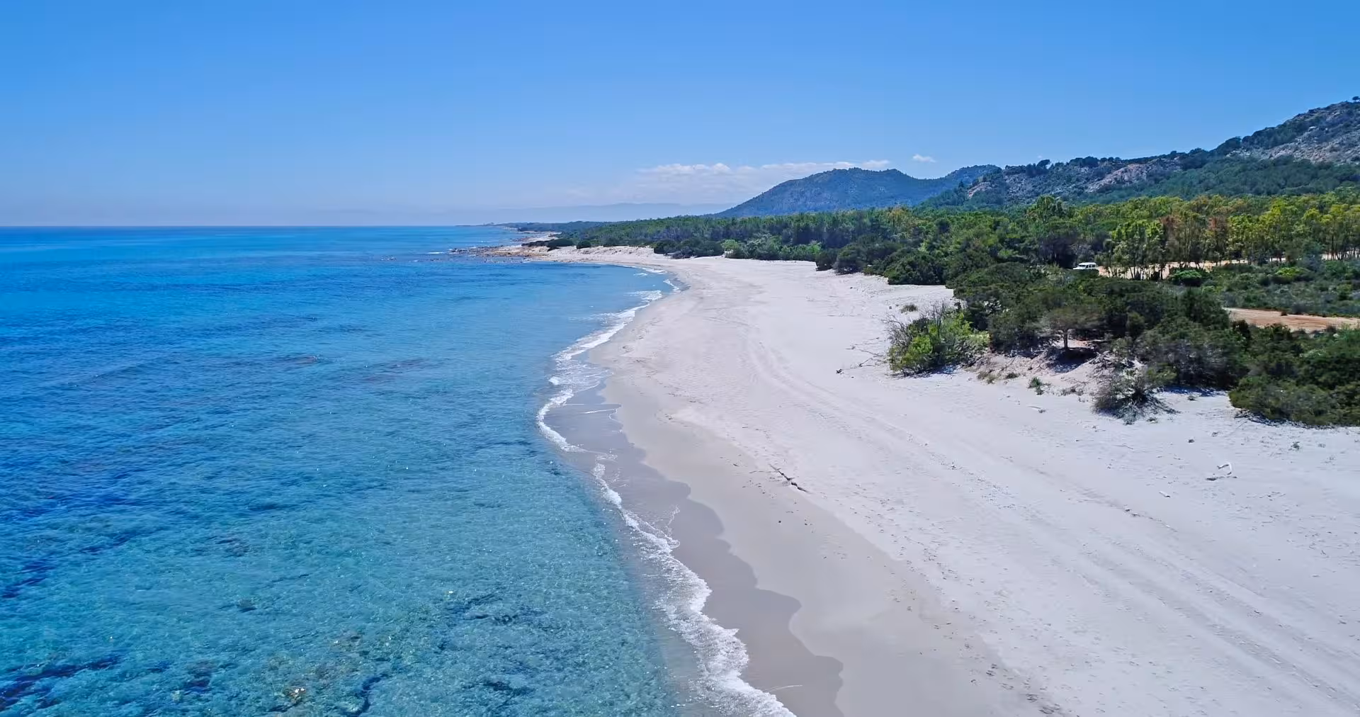 Pristine white sand beach and clear turquoise waters at Capo Comino, featured in the Orosei Jeep tour.