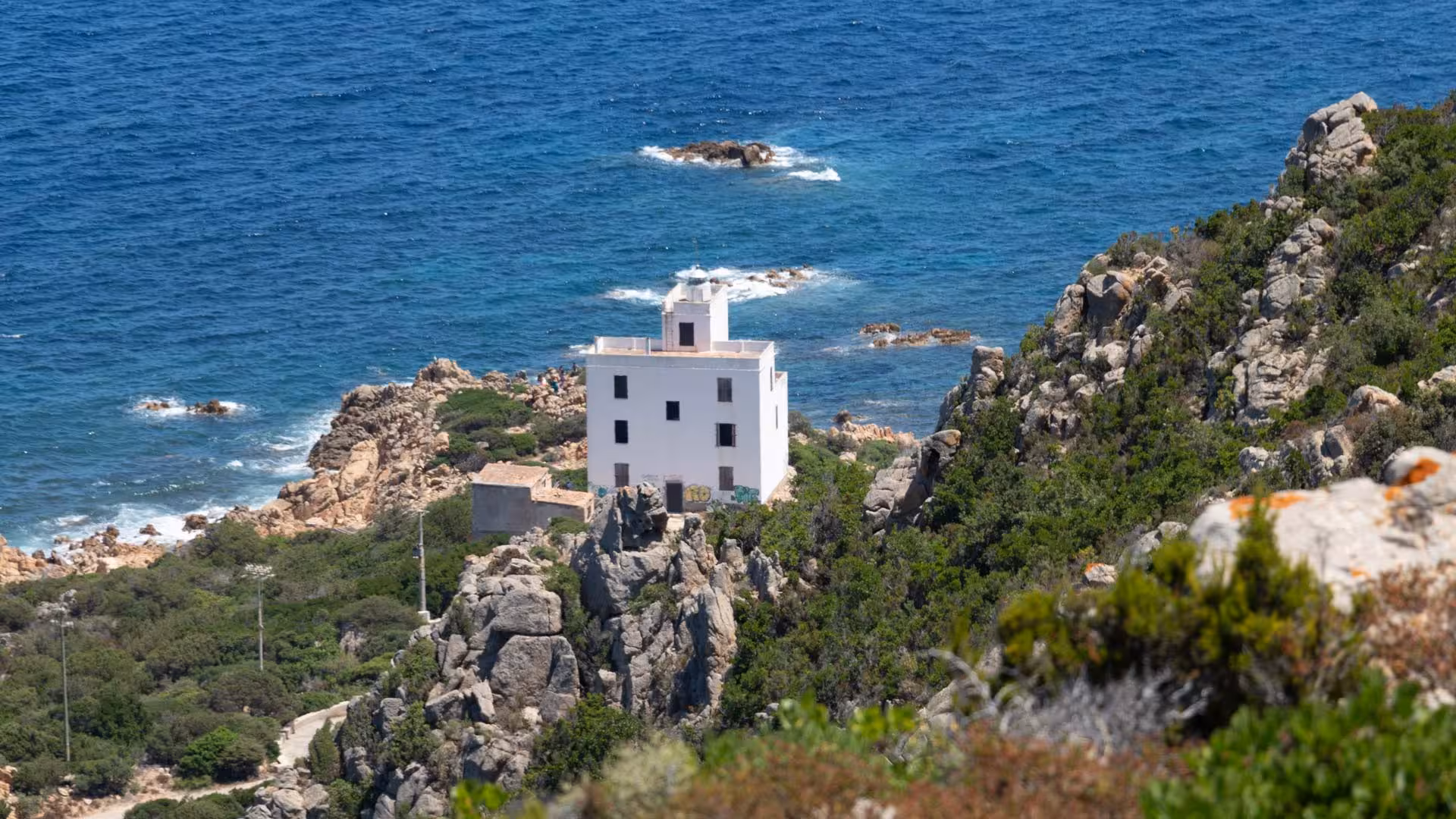 Discover the picturesque Capo Comino lighthouse nestled on rugged cliffs during the Orosei Jeep tour adventure.