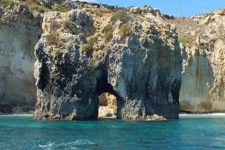 Scenic rock arch formation on Ortigia coast with turquoise waters during Syracuse boat tour dolphin sighting trip