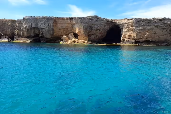 Stunning turquoise waters and rocky sea caves along the Ortigia coastline on a Syracuse boat tour Sicily