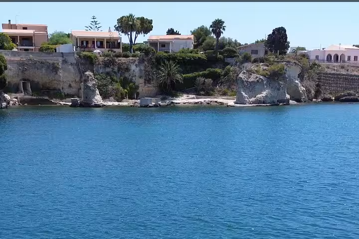 Stunning Ortigia coastline with white rock formations and blue sea viewed from Syracuse boat tour excursion