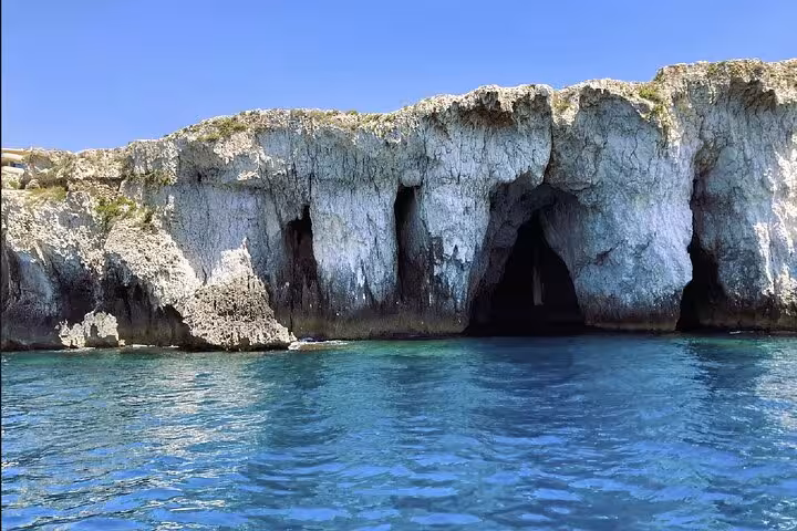 Dramatic limestone sea caves along Ortigia coast with crystal clear blue water on Syracuse dolphin sighting boat tour