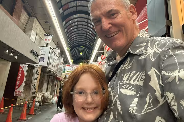 Father and daughter smiling in a covered shopping arcade in Osaka, Japan
