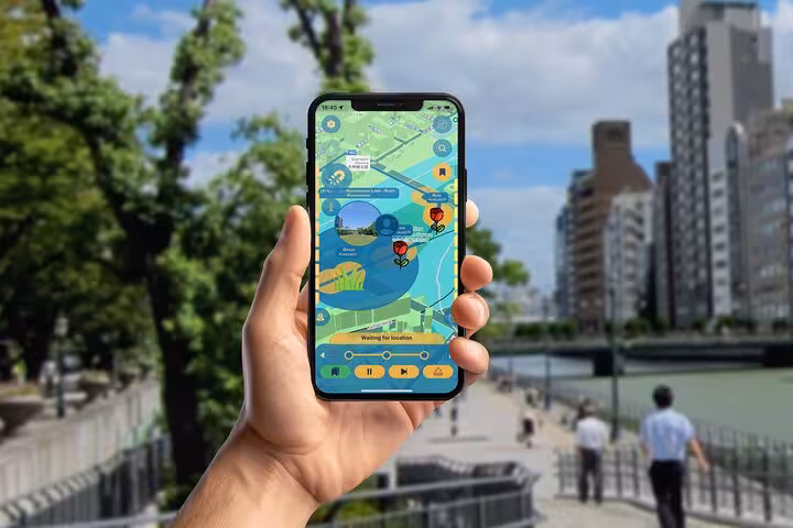 Hand holding smartphone with self-guided walking tour app map in Osaka riverside park