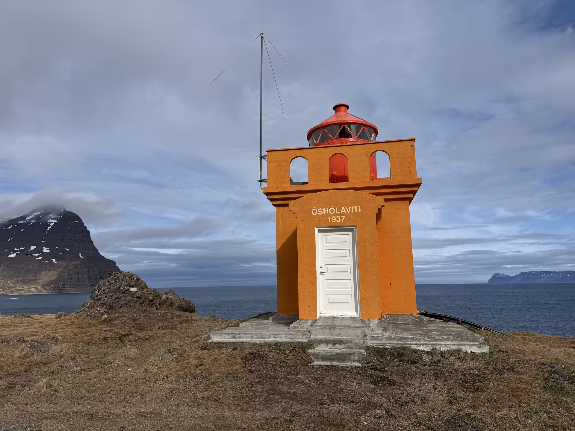 Óshólaviti lighthouse built in 1937, an orange tower with red dome overlooking a fjord in Iceland's Westfjords