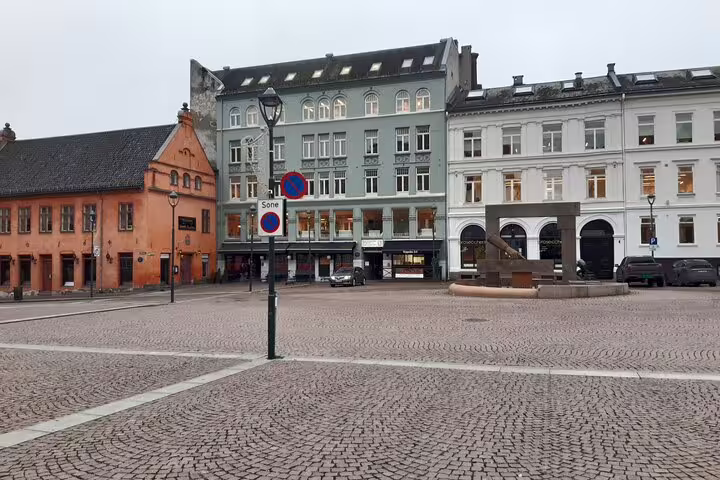 Cobblestone town square in Oslo with historic European buildings and street lamp on overcast day