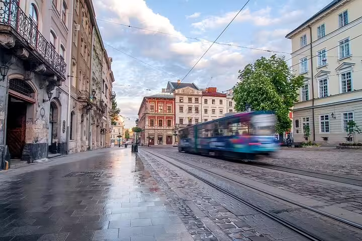 Tram speeding through wet cobblestone streets lined with historic European buildings at dusk