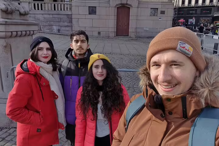 Four young tourists on a guided walking tour in Oslo city square during winter