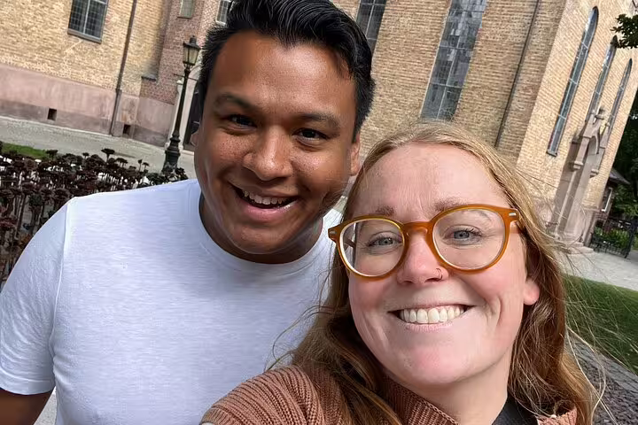 Two smiling tourists on Oslo Viking Quest guided walking tour near historic stone building