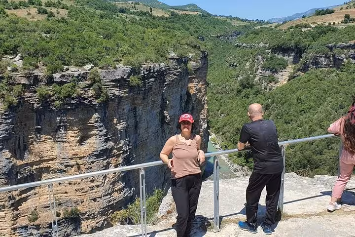 Visitors enjoy breathtaking views of the lush Osum Canyon from a scenic lookout point in Albania.