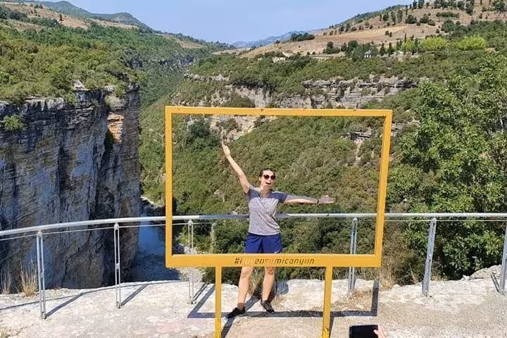 Visitor enjoying a scenic view at Osum Canyon with lush greenery and dramatic cliffs, perfect for sightseeing and exploration.