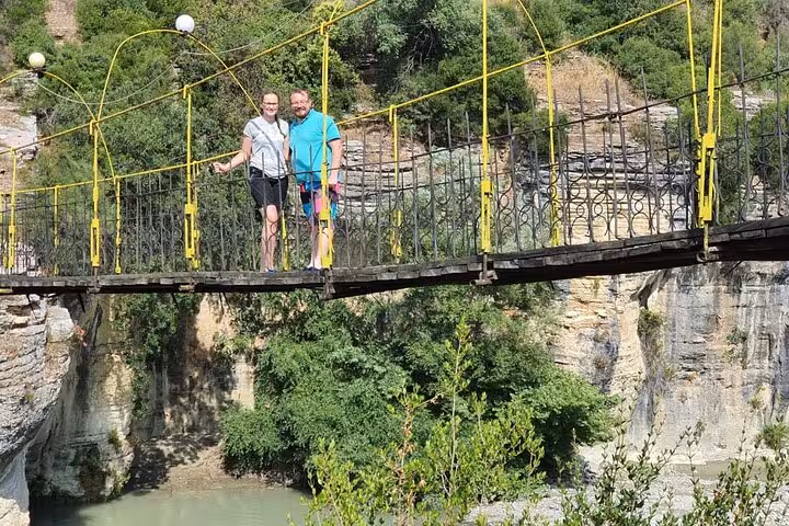 Tourists enjoying breathtaking views from a suspension bridge in Osum Canyon, perfect for sightseeing and exploration.