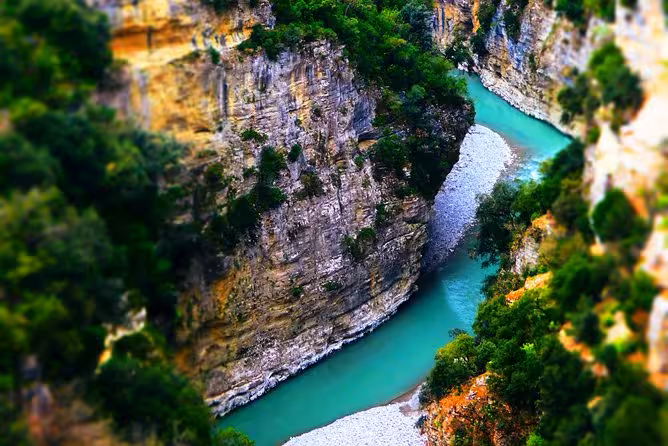 Stunning view of Osum Canyon's turquoise river winding through lush cliffs in southern Albania, perfect for adventure tours.
