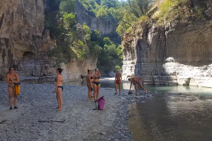 Group of tourists exploring the breathtaking rocky landscapes and pristine river of Osum Canyon.
