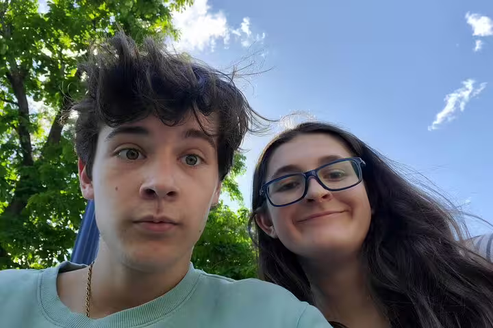 Two young people taking a selfie outdoors in Ottawa with trees and blue sky behind them