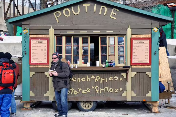 Man eating poutine at a classic wooden food stand serving French fries in Ottawa winter