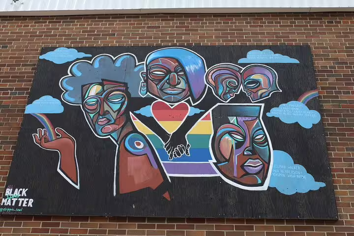 Colorful street art mural featuring abstract faces, Pride flag, rainbow, and Black Lives Matter text on brick wall in Ottawa