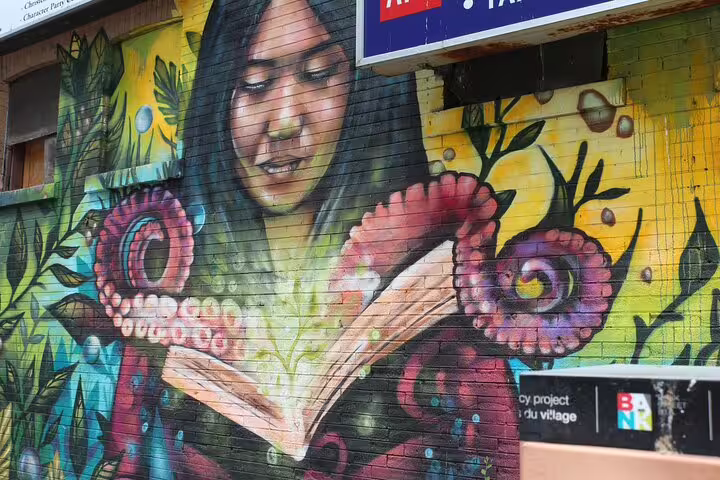 Street art mural of a woman reading a book with octopus tentacles on a brick wall in Ottawa