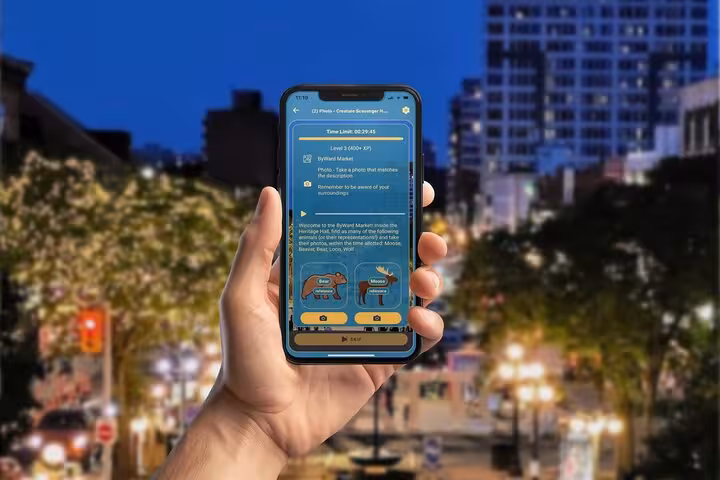 Hand holding smartphone displaying Ottawa wildlife scavenger hunt app with moose and bear icons at night