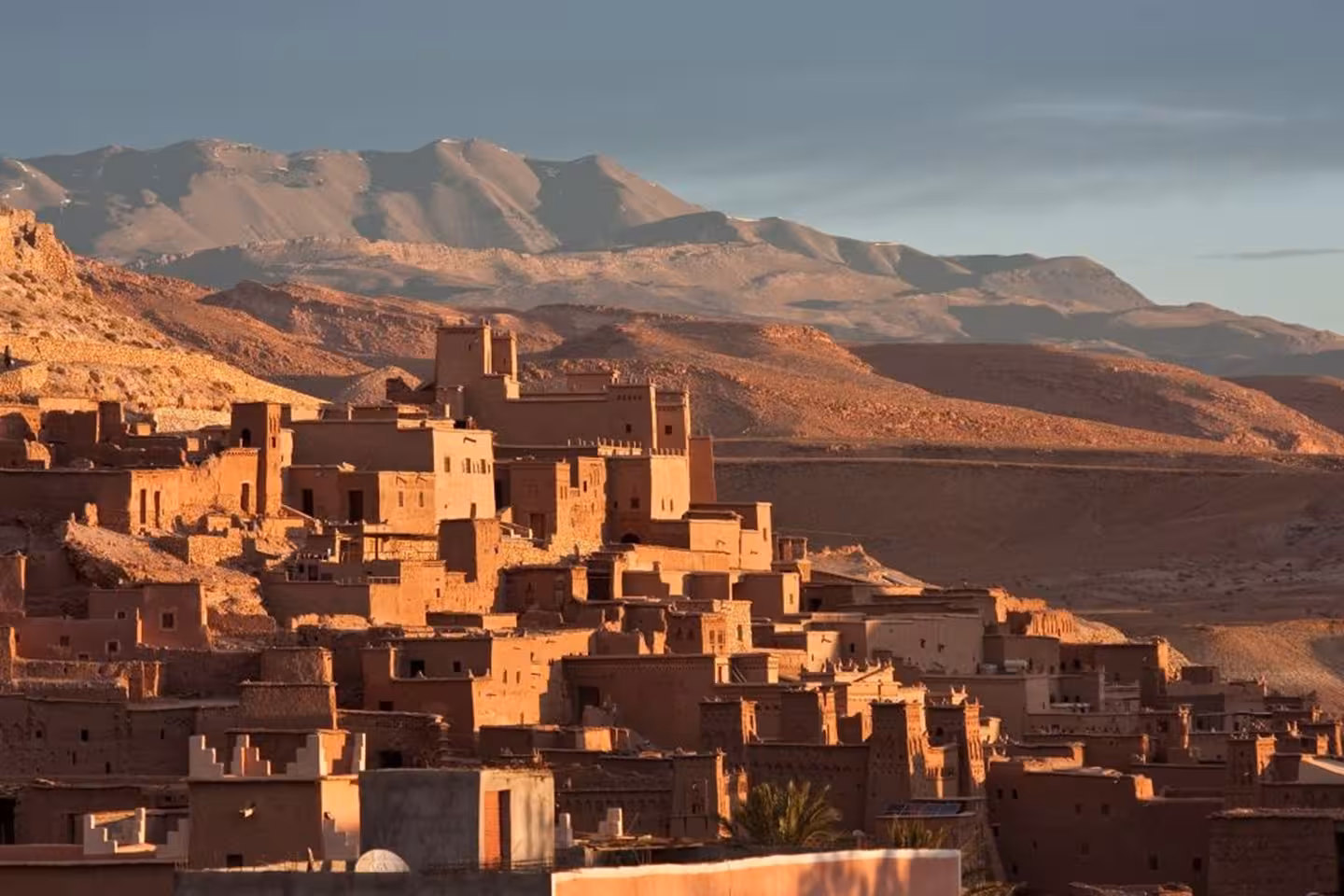 Scenic view of Ouarzazate's ancient clay architecture set against the Atlas Mountains on a Sahara tour.
