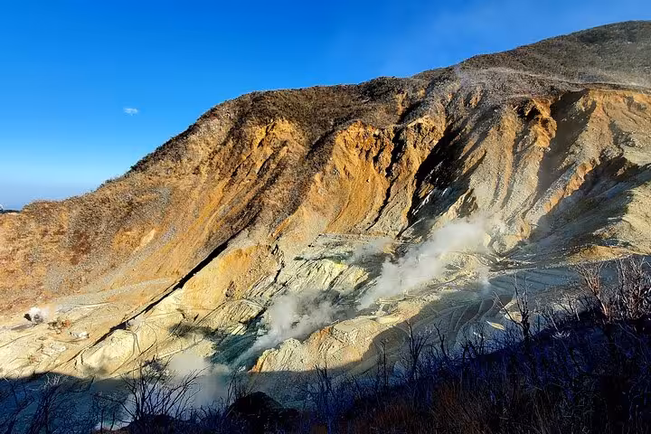 Close-up view of Owakudani active volcanic crater with sulfur steam rising from rocky Hakone landscape