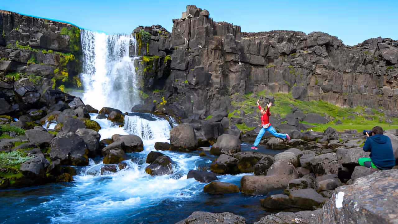 Child jumping on rocks beside Öxará waterfall on Iceland's Golden Circle tour from Reykjavik