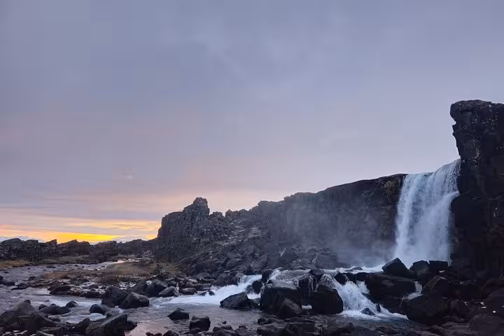 Öxará waterfall cascading over black volcanic rocks at sunset in Þingvellir National Park, Iceland