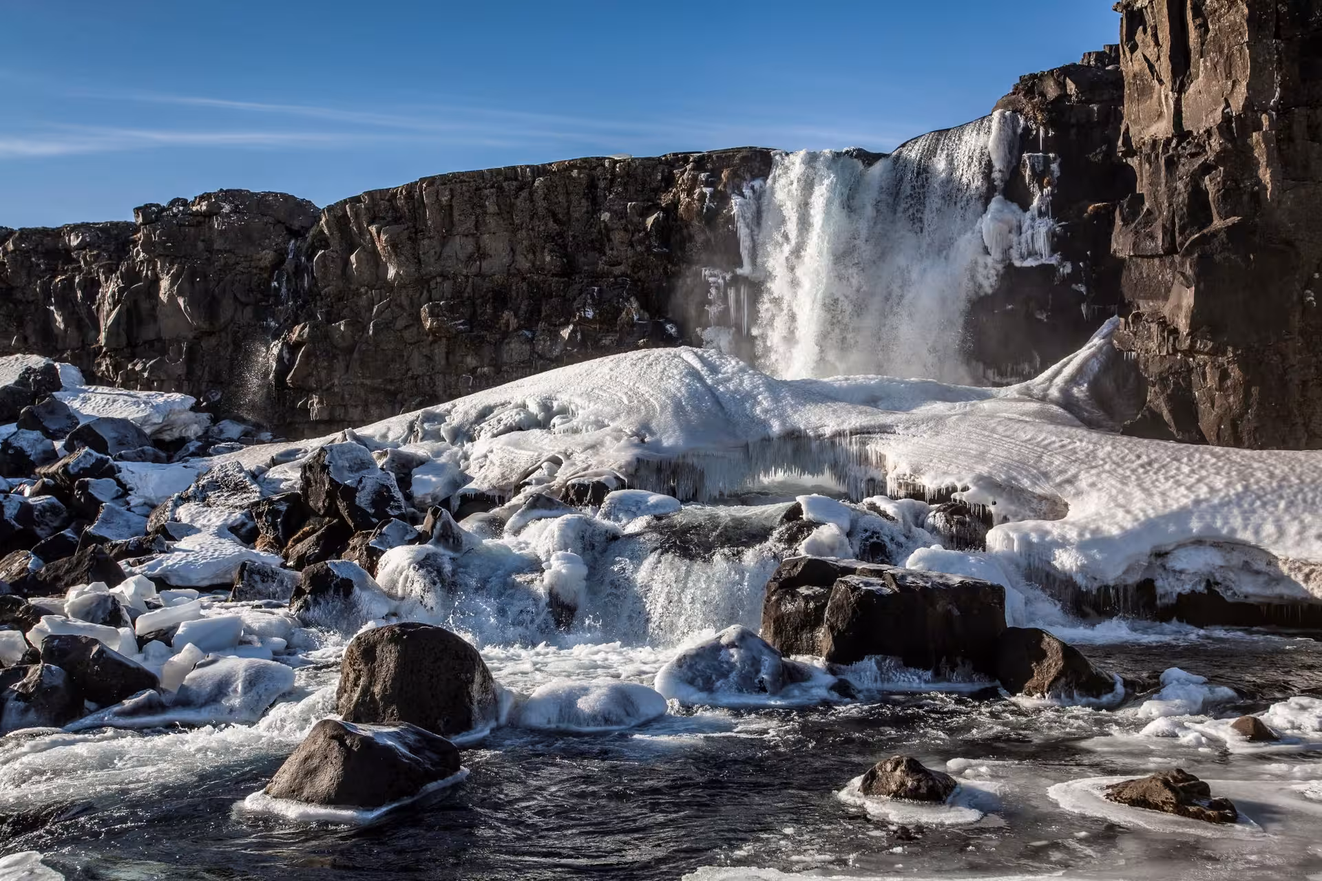 Majestic Öxarárfoss waterfall cascading over icy rocks in Iceland's national park on a 4-day stopover tour.