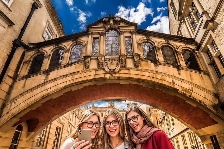 Group of friends taking a selfie under Oxford's iconic Bridge of Sighs during a private day trip from London with lunch included.