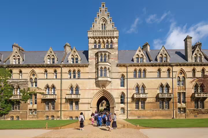 Tourists explore the iconic architecture of Christ Church College in Oxford on a sunny private day trip from London with lunch.