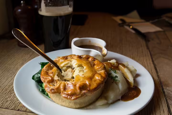 Traditional British meat pie with mashed potatoes and gravy, served with a pint, highlights the authentic Oxford day trip lunch experience.