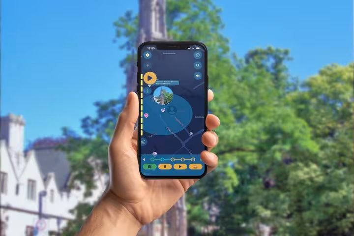 Hand holding smartphone displaying Oxford self-guided walking tour GPS app with interactive map