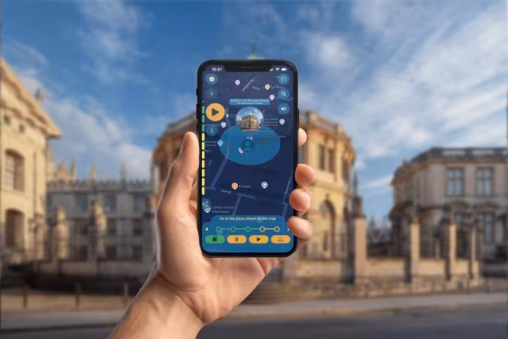 Hand holding smartphone displaying Oxford self-guided walking tour GPS app with city map and landmarks